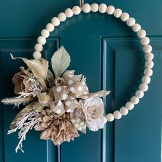 a wreath is hanging on the front door with flowers and leaves in it, along with beads