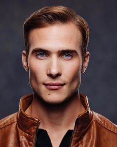 a man with blue eyes wearing a brown leather jacket