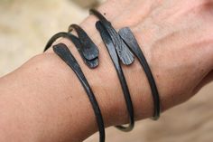 a woman's arm with three bracelets on it, one is black and the other is silver