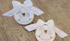 two personalized christmas ornaments on a wooden table with ribbons and bows in the shape of an ornament