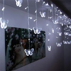 some lights hanging from the ceiling in a room with pictures and butterflies attached to it