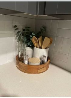 a wooden tray with utensils and spoons in it on a kitchen counter