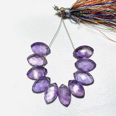 a purple necklace with lots of different colored beads hanging from it's side on a white surface