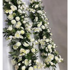 white flowers are arranged on the side of a wall