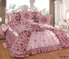 a bed with pink ruffled sheets and pillows