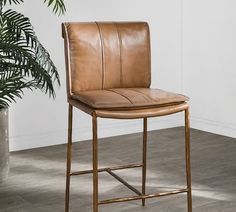 a brown leather chair sitting next to a potted plant