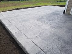 a concrete patio in front of a house with grass and dirt on the ground next to it