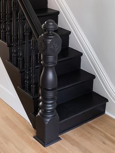 a black stair case sitting on top of a wooden floor next to a banister