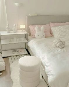 a bedroom with white bedding, pillows and stuffed animals on the headboard in front of the bed