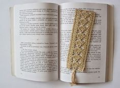 an open book with crochet on it and a tassel in the middle