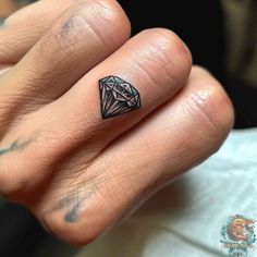 a person's hand with a diamond tattoo on it