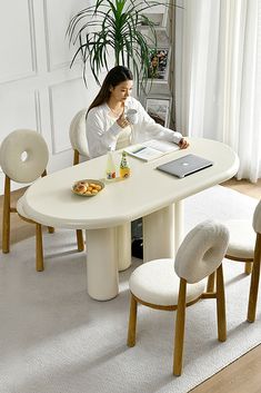 a woman sitting at a white table with two chairs and a laptop on top of it