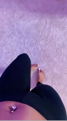 a woman laying on the ground with her feet up and wearing high heels, in front of a purple wall