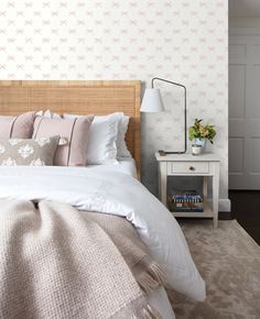 a bed with white sheets and pillows in a bedroom next to a wallpapered wall