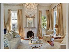 a living room filled with furniture and a chandelier hanging from the ceiling over a fire place