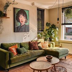 a living room filled with green couches next to a window covered in plants and potted plants