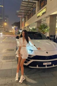 a woman standing next to a white sports car