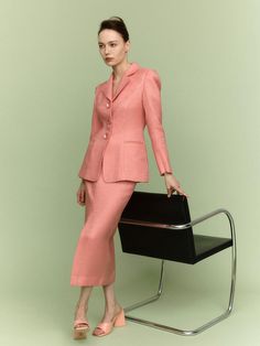 a woman standing next to a chair in a pink suit