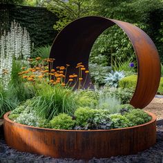 an outdoor garden with lots of plants and flowers in the center, surrounded by gravel