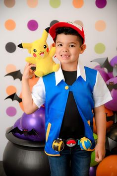 a young boy holding a stuffed toy in front of a wall with balloons and decorations