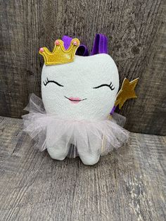 a white stuffed animal with a purple crown on it's head and tutu