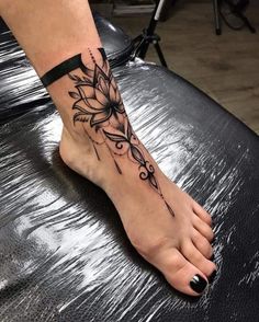 a woman's foot with a flower tattoo on her left leg and black ink