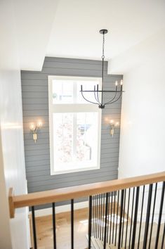 an empty room with a chandelier hanging from the ceiling, and a window in the corner