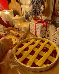 a pie with lattice design on it sitting on a table next to candles and christmas decorations