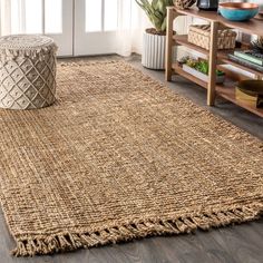 a living room area with a rug, coffee table and potted plant