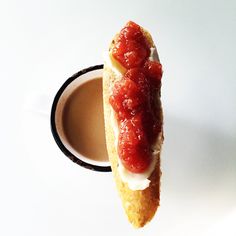 a piece of bread with ketchup on it next to a cup of coffee