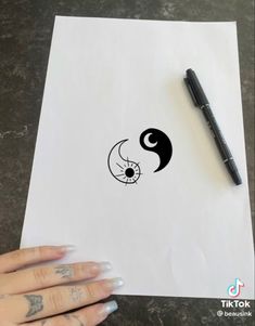 a person's hand holding a piece of paper with the yin symbol on it