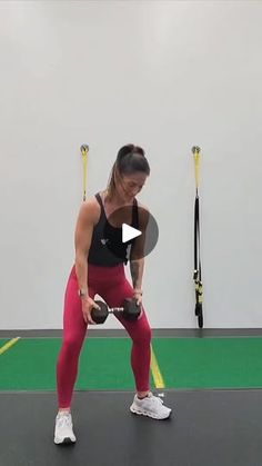 a woman in red leggings and black top holding a kettle while standing on a green mat