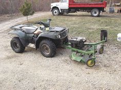 an atv parked on the side of a dirt road next to a truck and trailer