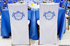 two blue and white chairs sitting next to each other in front of a table filled with flowers