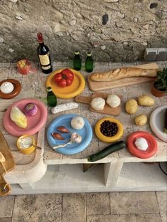 the table is full of different types of food and wine, including bread, tomatoes, olives, onions, cheese, garlic