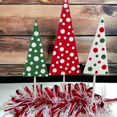 three small christmas trees are on sticks with candy canes in front of the top