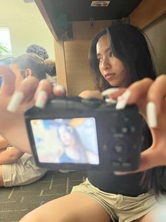 a woman taking a selfie with her cell phone while sitting on the floor in front of other people