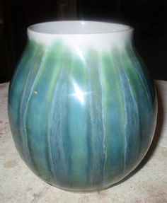 a green and white vase sitting on top of a table