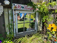 an old window has been decorated with flowers and plants in the back yard as if it were for a children's garden