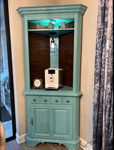 a blue china cabinet with a coffee maker on top