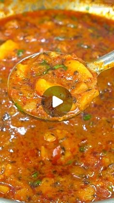 a ladle full of soup being stirred with a wooden spoon