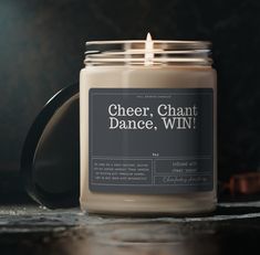 a candle is sitting on a table with a label that says cheer, chat, dance, win