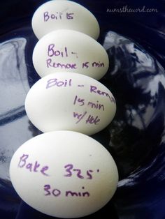 three white eggs with writing on them sitting in a blue bowl next to each other