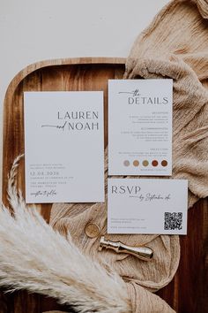 the wedding stationery is laid out on a wooden platter with some furs