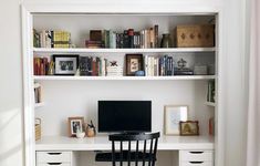 a desk with a computer on top of it and lots of books in the shelves