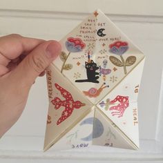 a hand holding an origami piece with cats on it