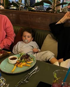 two women and a child sitting at a table with plates of food in front of them