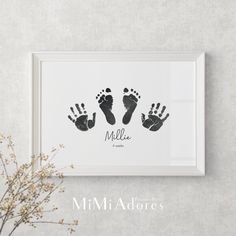 a framed photo with two baby's hand and foot prints in black ink on a white background