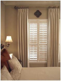 a bed sitting under a window next to a lamp