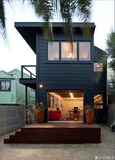 a black house with lots of windows and plants on the steps leading up to it